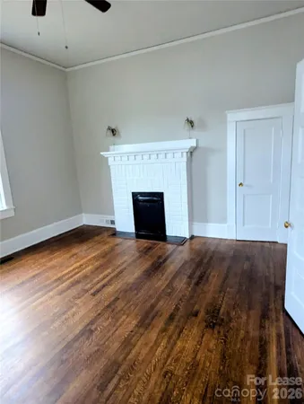 a view of empty room with wooden floor and fireplace