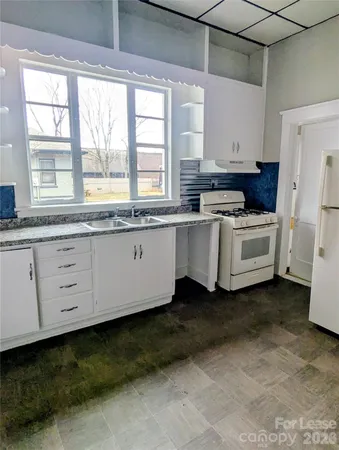 a kitchen with white cabinets and window