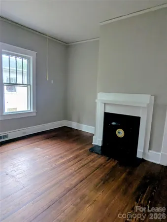 an empty room with wooden floor fireplace and windows