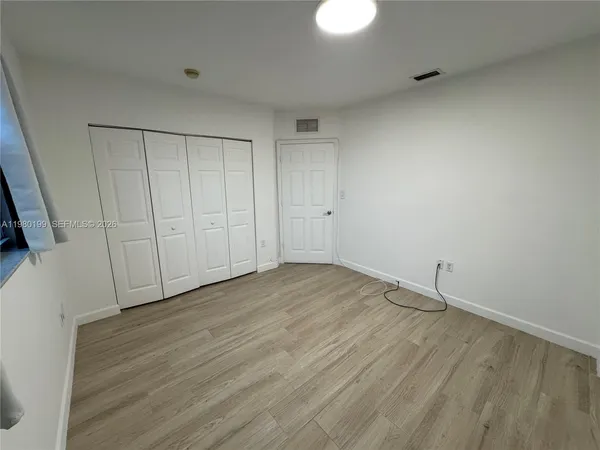 a view of an empty room with wooden floor