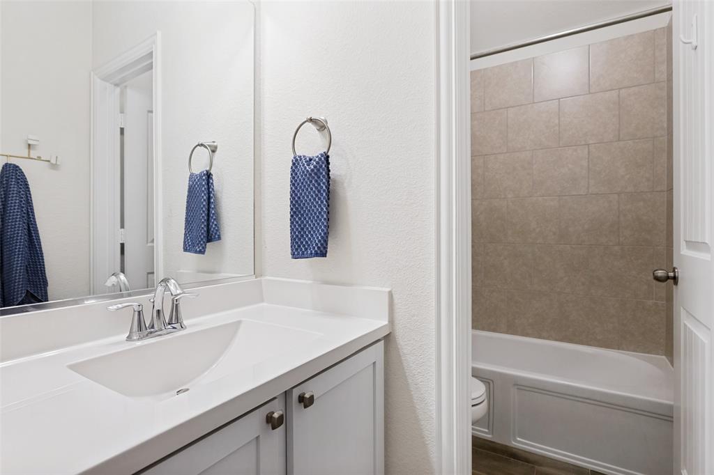 5556 Vaquero Road Fort Worth, TX 76126 - Photo 22 of 25 Bathroom featuring a white integrated sink with chrome faucet, a spacious vanity with white cabinetry, a large wall-mounted mirror, and a tub with tiled surround