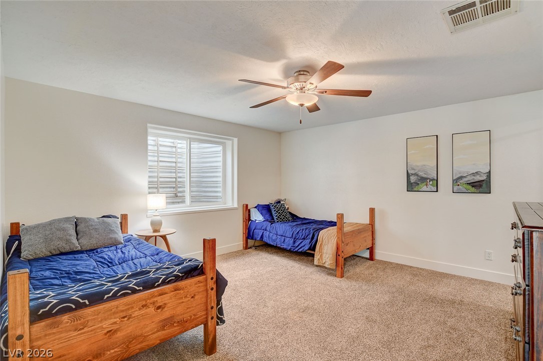 4362 Thistle Street Logandale, NV 89021 - Photo 56 of 99 A well-lit bedroom features plush carpeting and a modern ceiling fan, ideal for comfort.