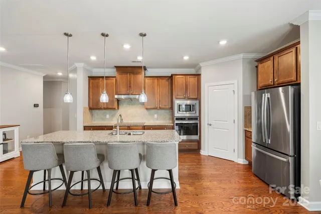 a kitchen with stainless steel appliances kitchen island granite countertop a refrigerator and a stove top oven