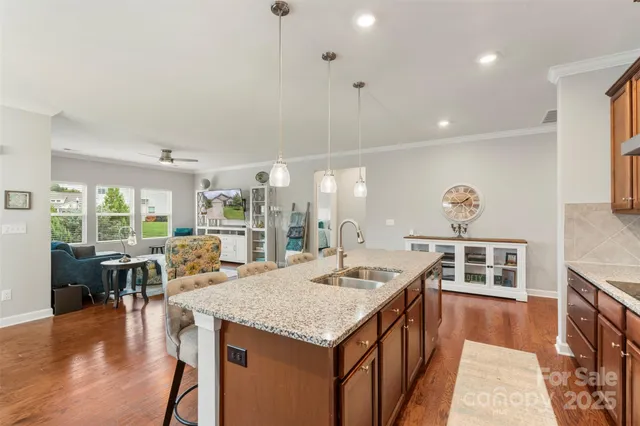 a view of a kitchen with kitchen island granite countertop a stove a sink a refrigerator dining table and chairs with wooden floor