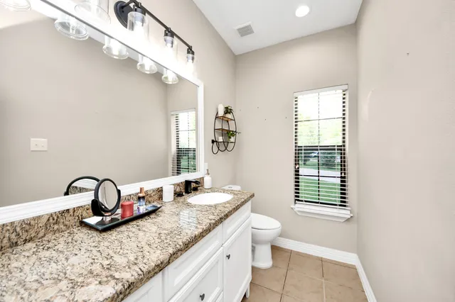a bathroom with a granite countertop double vanity sink a mirror and a shower