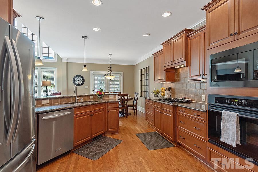 117 Bancroft Brook Drive Cary, NC 27519 - Photo 5 of 29 a kitchen with stainless steel appliances granite countertop wooden cabinets a sink dishwasher a stove and a refrigerator