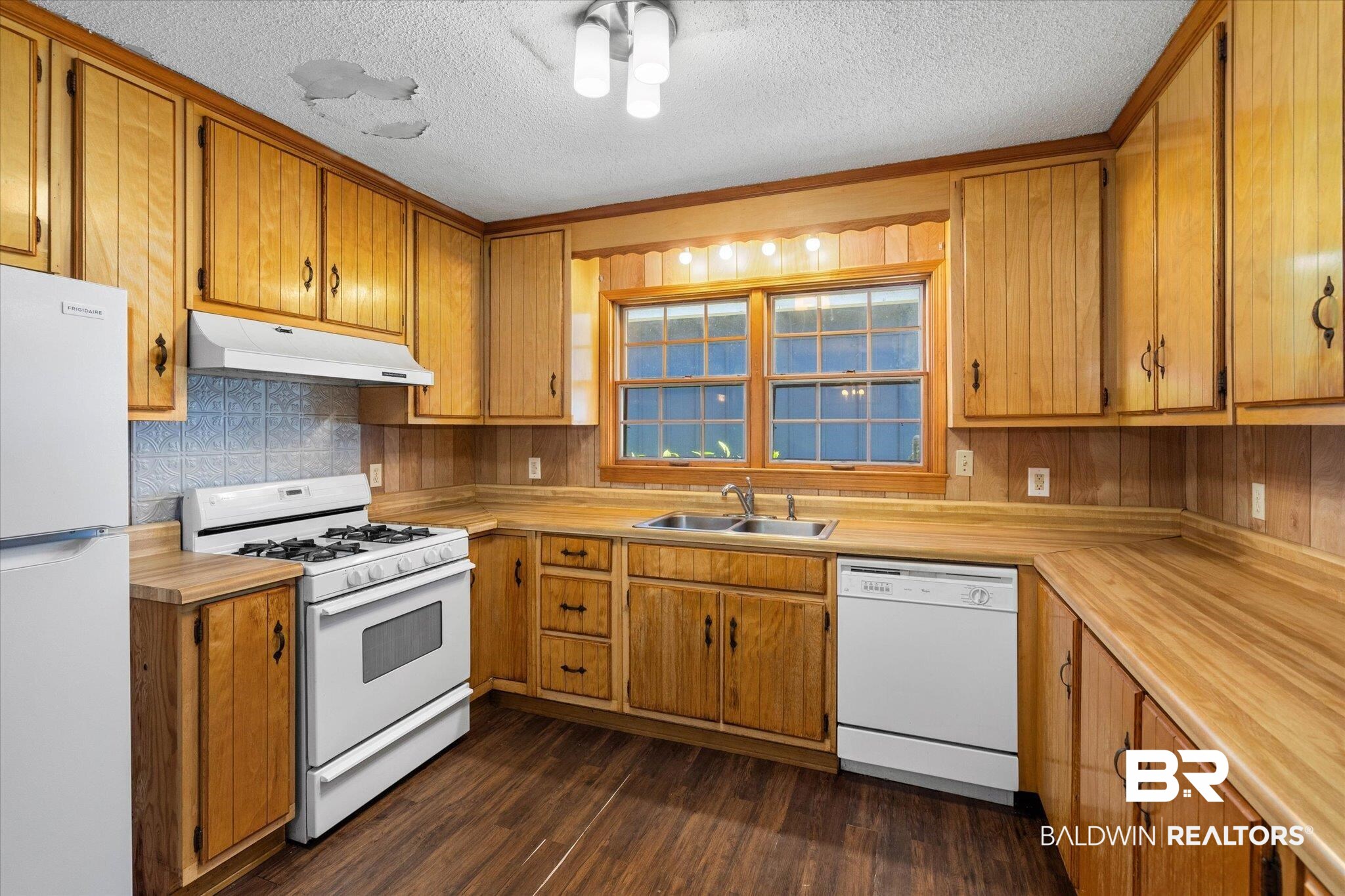 5503 Darring Street Satsuma, AL 36572 - Photo 8 of 31 Kitchen featuring white appliances, dark wood-style flooring, under cabinet range hood, a textured ceiling, and brown cabinetry