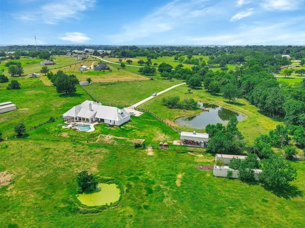 an aerial view of residential houses with outdoor space and trees