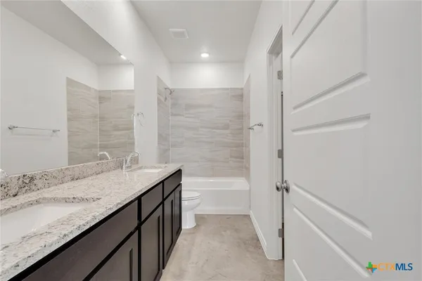 a bathroom with a granite countertop sink a toilet and shower