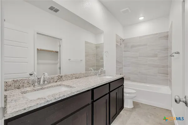 a bathroom with a granite countertop bathtub sink double and mirror