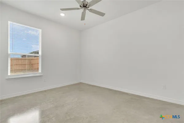 an empty room with a window and ceiling fan