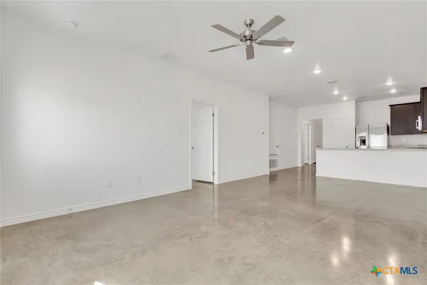 a view of a livingroom with a kitchen island with wooden floor and ceiling fan