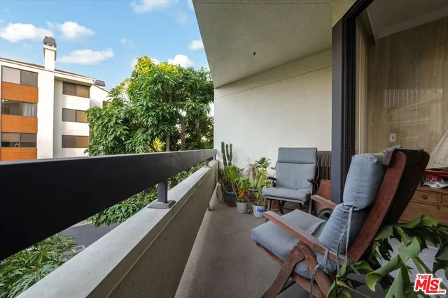 a balcony with chairs and a potted plant