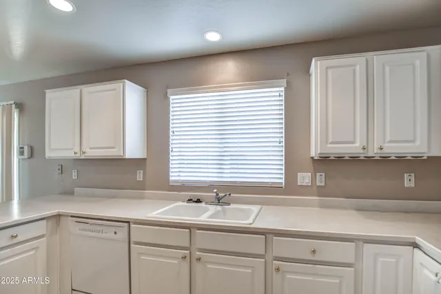 a kitchen with granite countertop white cabinets and sink