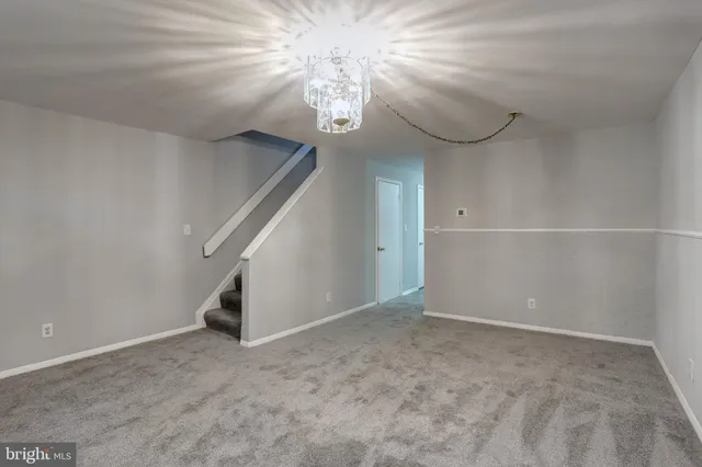 a view of an empty room with a chandelier fan