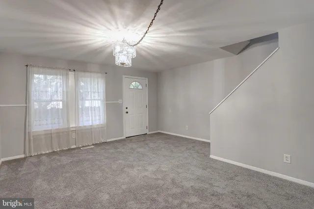 an empty room with chandelier fan and windows