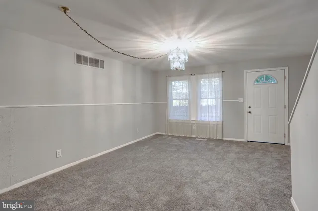 an empty room with windows and chandelier fan