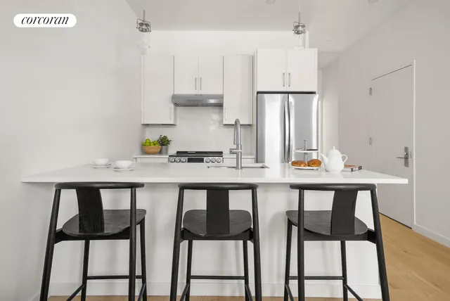 a kitchen with stainless steel appliances a refrigerator a sink a stove and white cabinets