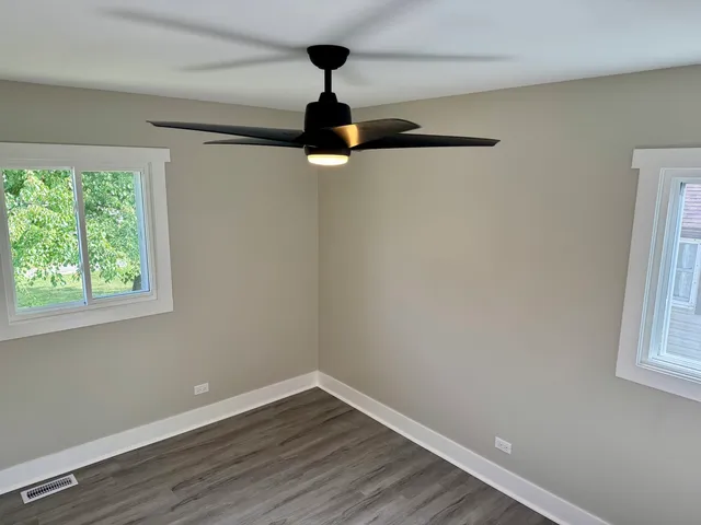 a view of empty room with wooden floor fan and window