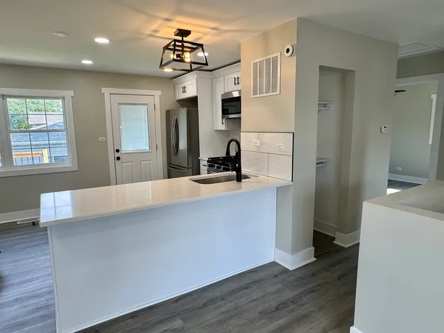 a view of a hallway with wooden floor and a living room