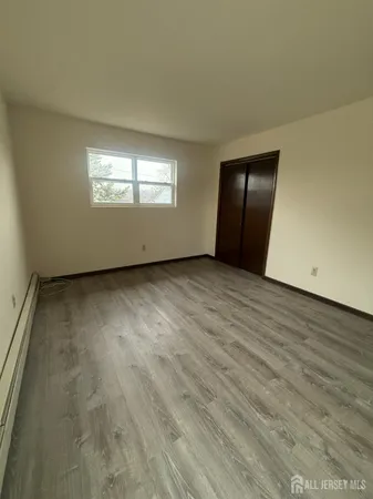 an empty room with wooden floor closet and windows