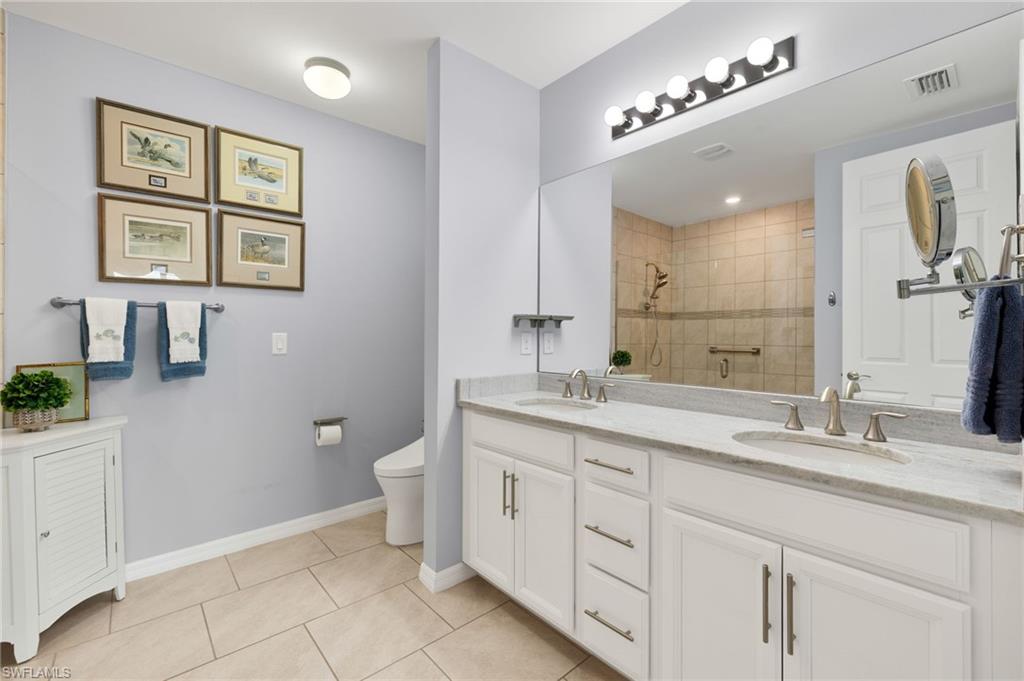 14615 Edgewater Circle Naples, FL 34114 - Photo 16 of 42 a bathroom with a double vanity sink and a mirror