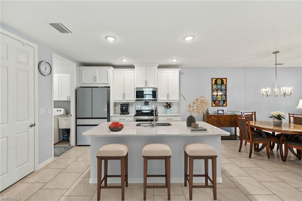 14615 Edgewater Circle Naples, FL 34114 - Photo 8 of 42 a kitchen with stainless steel appliances a table and chairs