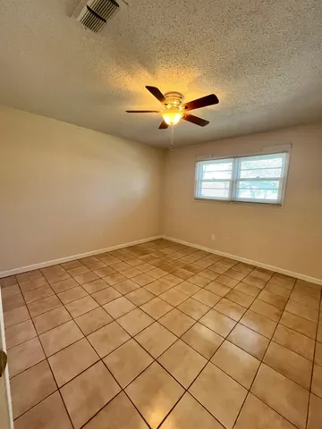 a view of an empty room and chandelier fan