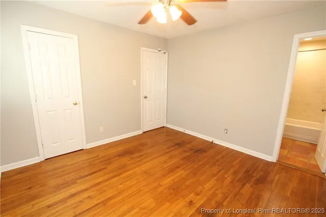 an empty room with wooden floor and fan