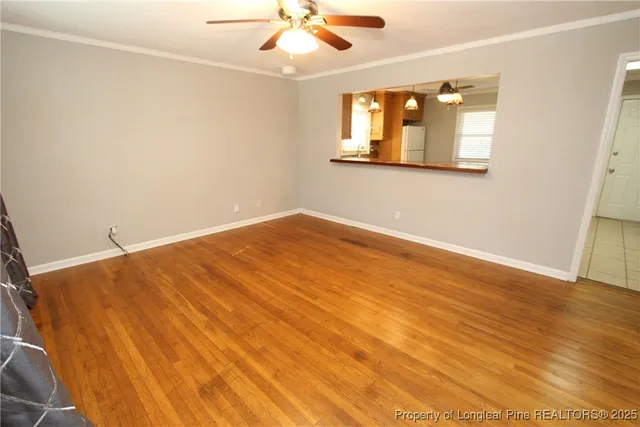 an empty room with wooden floor fan and windows