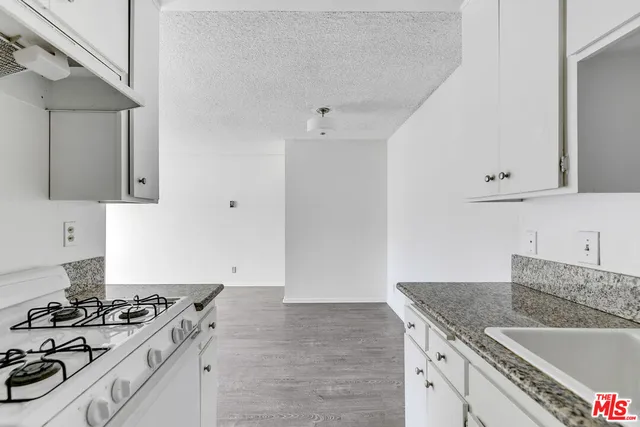 a kitchen with granite countertop a sink stove and cabinets
