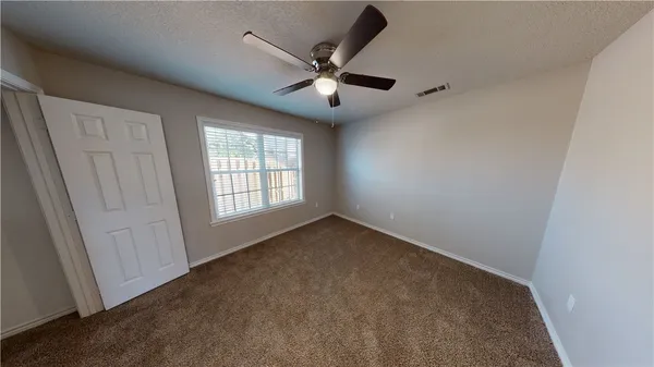 an empty room with ceiling fan and window