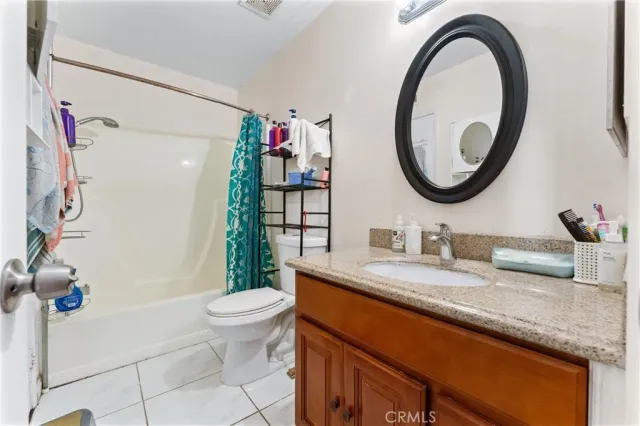 a bathroom with a granite countertop toilet a sink and a mirror