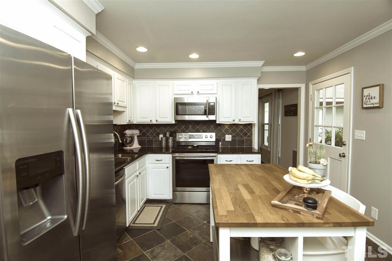 7408 Post Oak Road Raleigh, NC 27615 - Photo 11 of 27 a kitchen with stainless steel appliances granite countertop a refrigerator a stove a sink a dining table and chairs with wooden floor