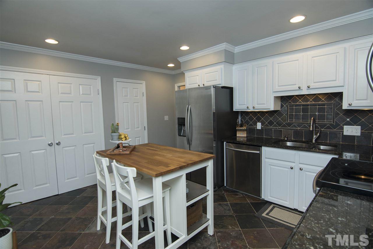 7408 Post Oak Road Raleigh, NC 27615 - Photo 12 of 27 a kitchen with a refrigerator a stove a sink and white cabinets