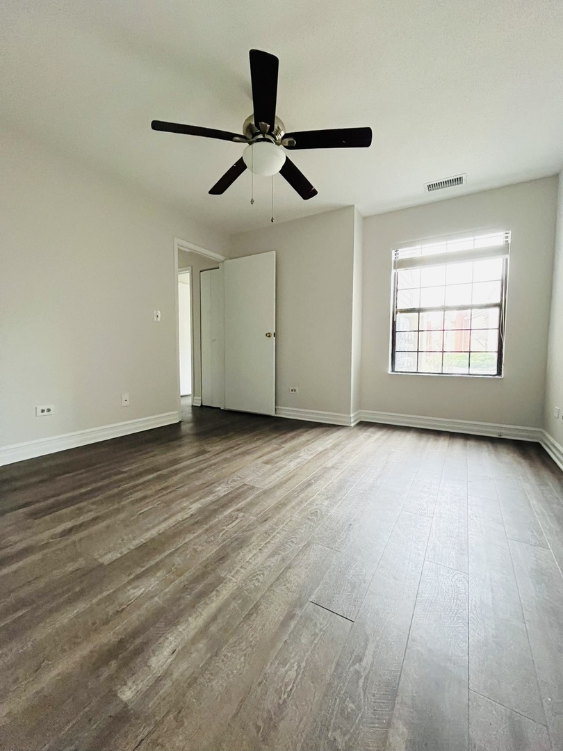2014 North Rand Road, Unit 108 Palatine, IL 60074 - Photo 11 of 16 an empty room with wooden floor ceiling fan and windows