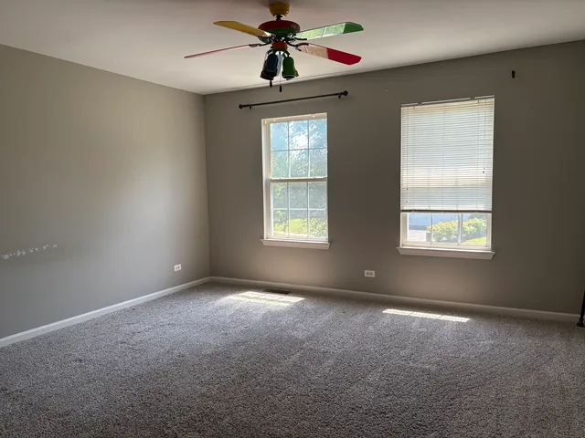 a view of an empty room with window and chandelier fan