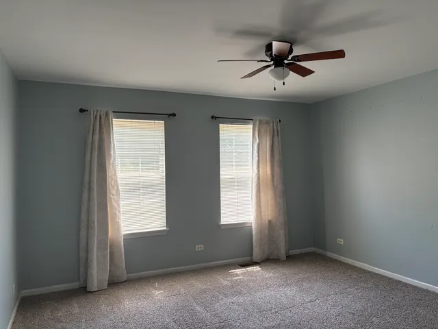 an empty room with fan and windows