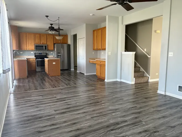 a kitchen with stainless steel appliances kitchen island granite countertop a stove a refrigerator and a view of living room