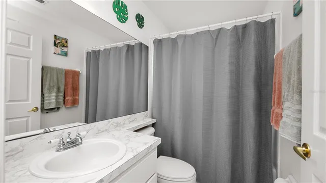 a bathroom with a sink a toilet and shower curtain