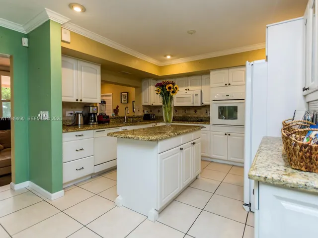 a kitchen with stainless steel appliances kitchen island granite countertop a refrigerator and a stove top oven