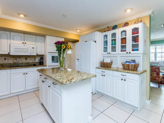a kitchen with granite countertop white cabinets and white appliances