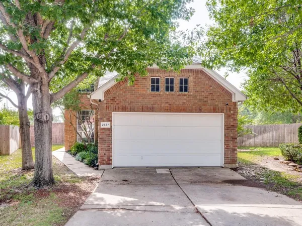a front view of a house with a yard and trees
