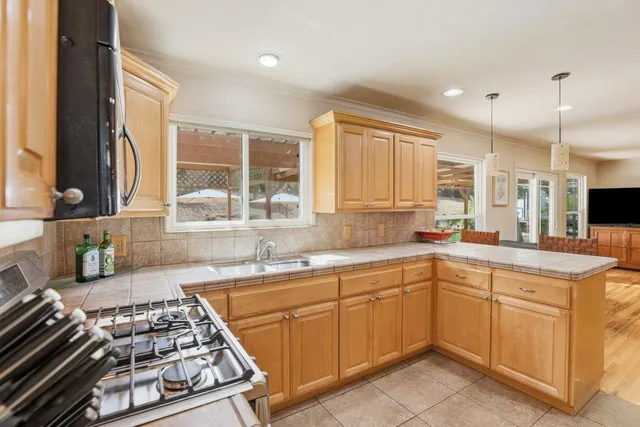 a kitchen with stainless steel appliances granite countertop a refrigerator a oven and white cabinets with wooden floor
