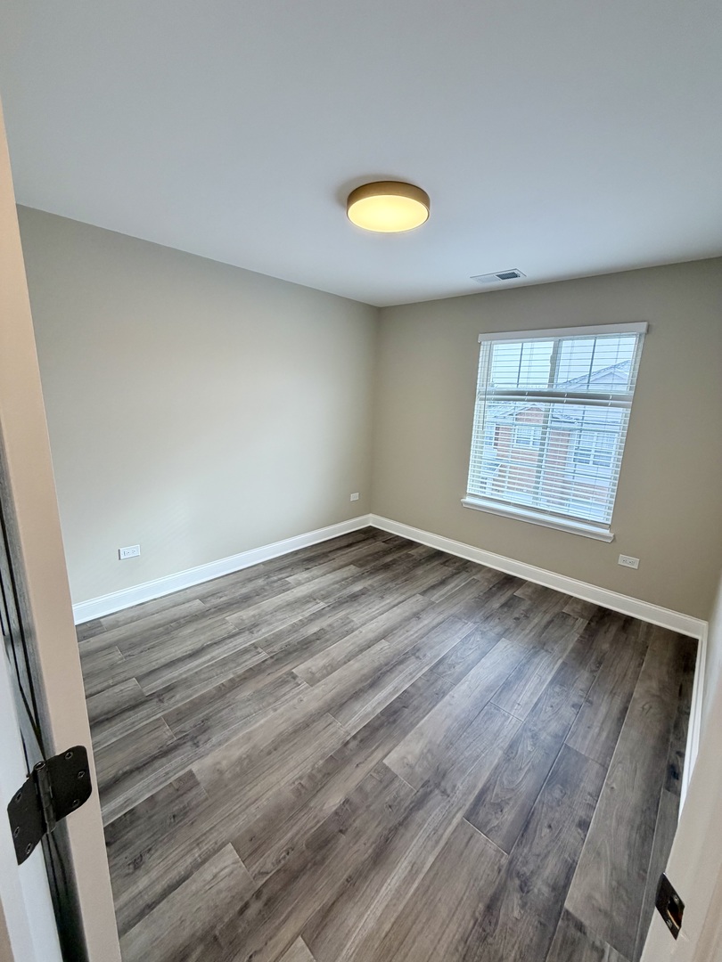 10233 Concord Lane, Unit C Bridgeview, IL 60455 - Photo 17 of 23 wooden floor in an empty room with a window