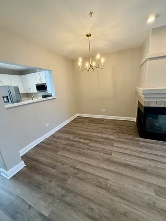 an empty room with wooden floor and kitchen view