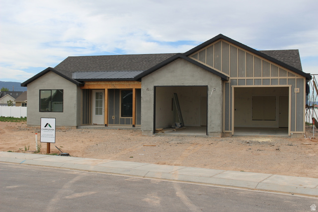 4933 East Remington Road Cedar City, UT 84721 - Photo 2 of 33 Newly constructed residence featuring a dark shingle roof, light gray stucco facade, an integrated covered entry with exposed wood beams, and a two-car garage