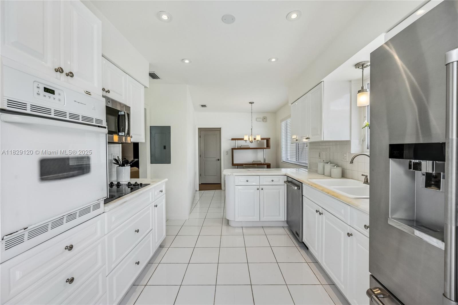 8811 Hawthorne Avenue Surfside, FL 33154 - Photo 19 of 47 a large white kitchen with stainless steel appliances granite countertop a sink a stove a refrigerator and cabinets