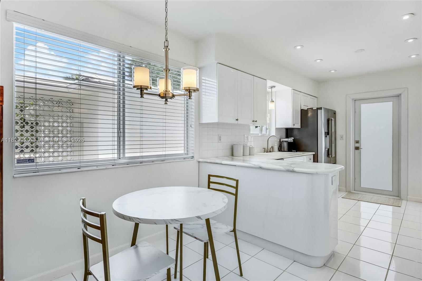 8811 Hawthorne Avenue Surfside, FL 33154 - Photo 21 of 47 a kitchen with stainless steel appliances kitchen island a table chairs in it and white cabinets