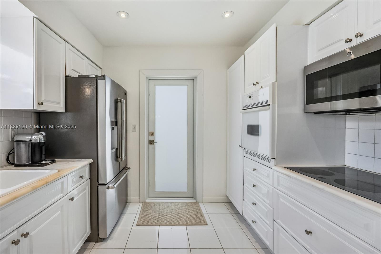 8811 Hawthorne Avenue Surfside, FL 33154 - Photo 22 of 47 a kitchen with white cabinets and stainless steel appliances